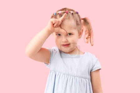 Photo for Funny little girl showing loser gesture on pink background - Royalty Free Image