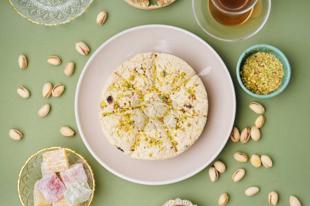 Téléchargez les photos : Assiette de savoureuse halva Tahini aux pistaches et délice turc sur fond vert - en image libre de droit