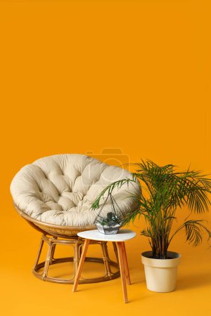 Foto de Acogedor sillón, mesa y plantas de interior sobre fondo naranja - Imagen libre de derechos