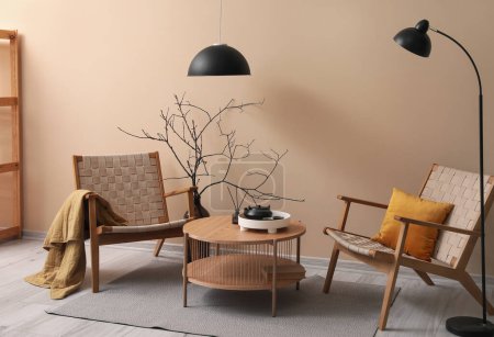 Téléchargez les photos : Intérieur du salon avec fauteuils confortables et table basse près du mur beige - en image libre de droit