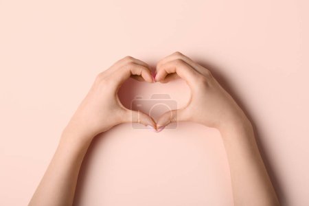 Photo for Woman making heart with her hands on beige background - Royalty Free Image