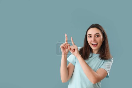 Téléchargez les photos : Jeune femme pointant quelque chose sur fond bleu - en image libre de droit