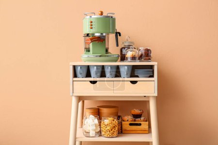Table avec machine à café, snacks et tasses près du mur beige