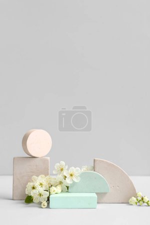 Foto de Podios decorativos y rama floreciente sobre fondo gris - Imagen libre de derechos