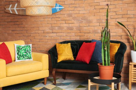 Foto de Interior de la elegante sala de estar con cómodos sofás, cactus y tabla de surf - Imagen libre de derechos