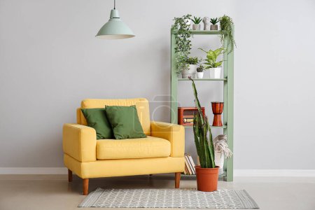 Foto de Interior de la sala de estar con sillón acogedor, cactus grande en olla y estantería - Imagen libre de derechos
