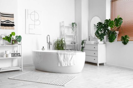 Photo for Interior of light bathroom with bathtub and Monstera houseplant - Royalty Free Image