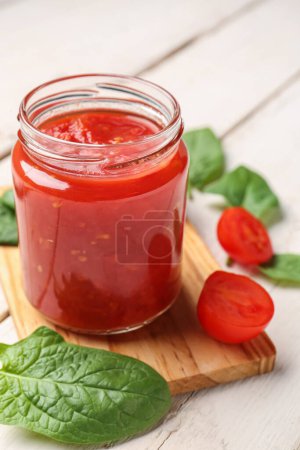 frasco con sabrosa salsa de tomate sobre fondo de madera clara, primer plano