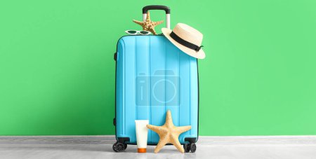 Téléchargez les photos : Valise avec accessoires de plage près du mur vert - en image libre de droit
