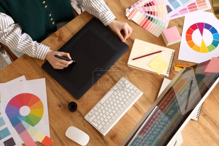 Photo for Female graphic designer working with tablet on table in office, top view - Royalty Free Image