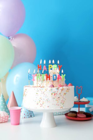 Photo for Birthday cake with different sweets on table near blue wall - Royalty Free Image