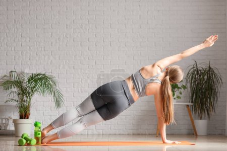 Foto de Mujer joven deportiva haciendo yoga en casa - Imagen libre de derechos