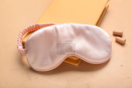 Foto de Tapones para los oídos con portátil y máscara para dormir sobre fondo beige - Imagen libre de derechos