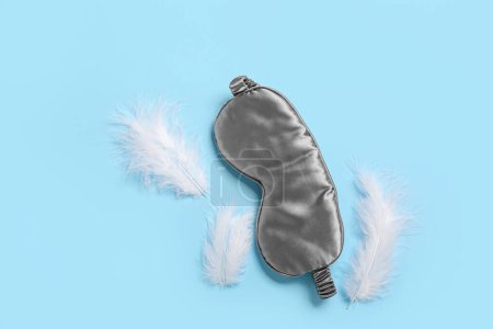 Photo for Sleeping mask and feathers on blue background - Royalty Free Image