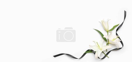 Beautiful lily flowers and black funeral ribbon on white background with space for text