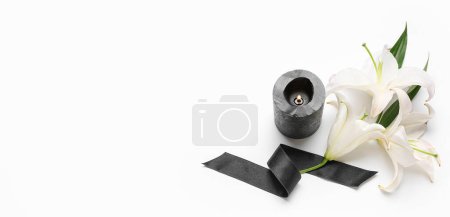 Foto de Flores de lirio, cinta funeraria negra y vela encendida sobre fondo blanco con espacio para texto - Imagen libre de derechos