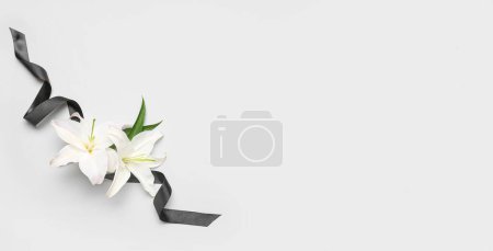 Schwarzes Trauerband und schöne Lilienblüten auf weißem Hintergrund mit Platz für Text
