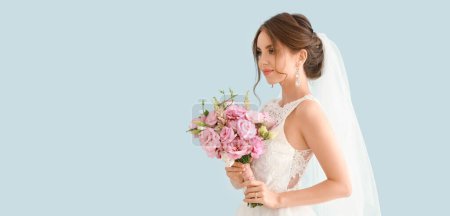 Téléchargez les photos : Portrait de belle jeune mariée avec bouquet de mariage sur fond bleu clair avec espace pour le texte - en image libre de droit