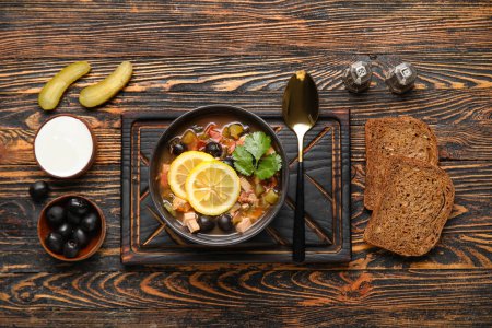 Téléchargez les photos : Bol de soupe Hodgepodge savoureuse avec crème sure et pain sur fond de bois - en image libre de droit