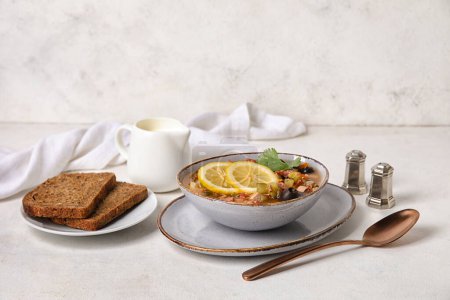 Téléchargez les photos : Bol de soupe Hodgepodge savoureuse avec du pain sur fond clair - en image libre de droit
