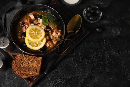 Téléchargez les photos : Bol de soupe Hodgepodge savoureuse avec du pain sur fond sombre - en image libre de droit