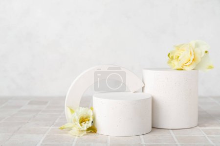 Photo for Decorative plaster podiums with daffodils on grey tile against white wall - Royalty Free Image
