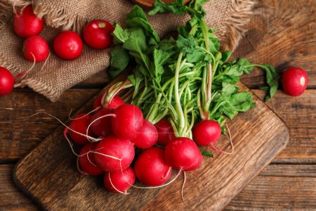 Photo for Board of fresh radishes with leaves on wooden background - Royalty Free Image