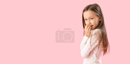 Foto de Niña mordiendo uñas sobre fondo rosa con espacio para texto - Imagen libre de derechos