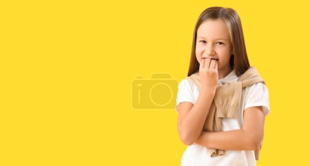 Foto de Niña mordiendo clavos sobre fondo amarillo con espacio para texto - Imagen libre de derechos