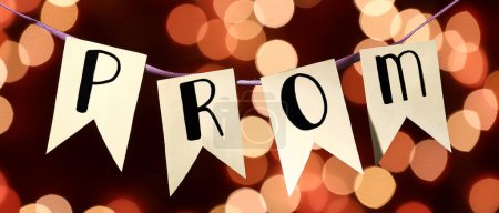 Hanging flags with word PROM on dark background with blurred lights