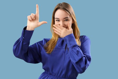 Mujer joven mostrando gesto perdedor sobre fondo azul
