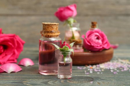 Photo for Bottles of cosmetic oil with rose extract and flowers on wooden table - Royalty Free Image