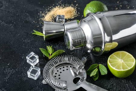Shaker, strainer and ingredients for preparing mojito on dark background