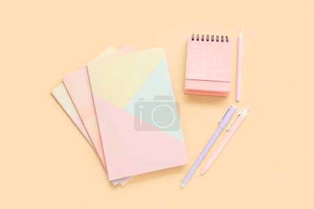 Flip paper calendar for May with notebooks and pens on beige background