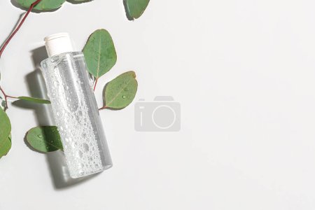 Foto de Botella de agua micelar con ramas de eucalipto sobre fondo claro - Imagen libre de derechos