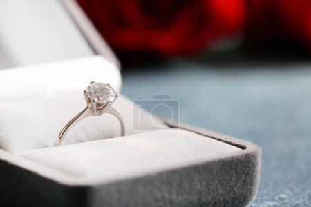 Box with engagement ring on blue background, closeup