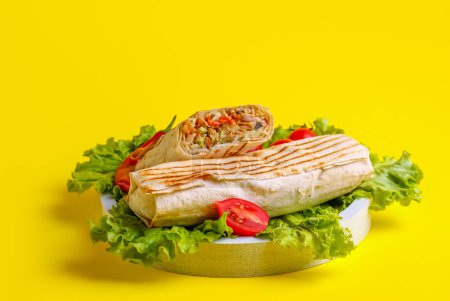 Téléchargez les photos : Assiette de shawarma savoureux avec laitue et tomates sur fond jaune - en image libre de droit