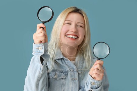 Photo for Young woman with magnifiers on blue background, closeup - Royalty Free Image