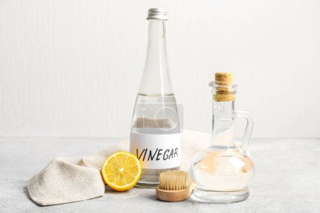 Bottles of vinegar, brush, lemon and napkin on table