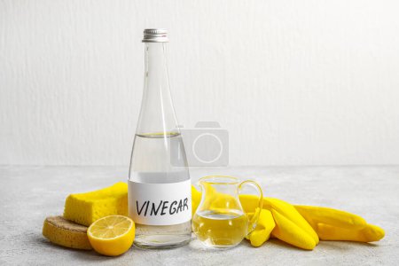 Eine Flasche Essig, Gummihandschuhe, Schwämme und Zitrone auf dem Tisch