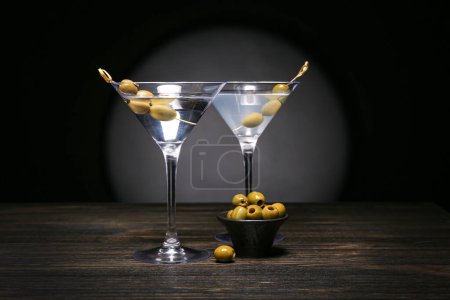 Photo for Glasses of tasty martini and olives on dark wooden table - Royalty Free Image
