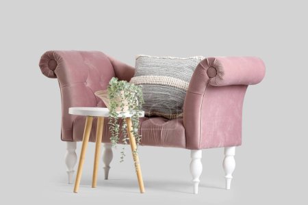 Téléchargez les photos : Canapé rose confortable et table basse avec plante d'intérieur sur fond gris - en image libre de droit