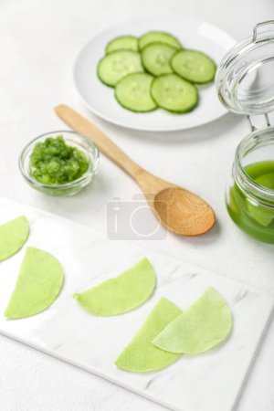 Photo for Cotton under-eye patches with cucumber slices on white table - Royalty Free Image