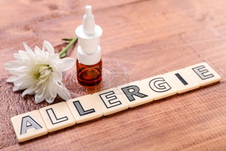 Photo for Word ALLERGIE with nasal drops and flower on wooden background - Royalty Free Image