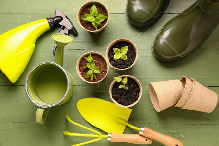 Photo for Peat pots with seedlings and gardening tools on green wooden background - Royalty Free Image