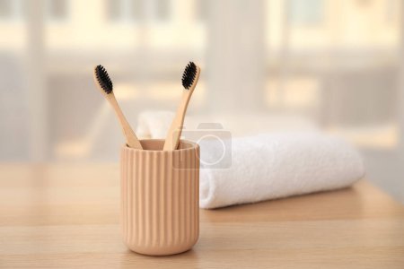 Foto de Soporte con cepillos de dientes de bambú en la mesa en la habitación, primer plano - Imagen libre de derechos