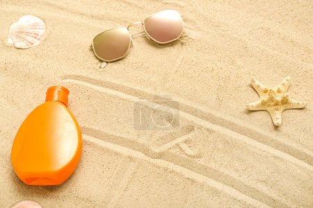Foto de Composición creativa con botella de crema protector solar con gafas de sol sobre arena - Imagen libre de derechos