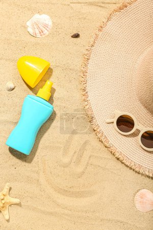Foto de Composición creativa con crema protectora solar, sombrero de verano y gafas de sol sobre arena - Imagen libre de derechos