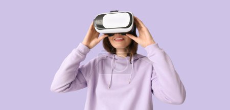 Pretty young woman with VR glasses on lilac background