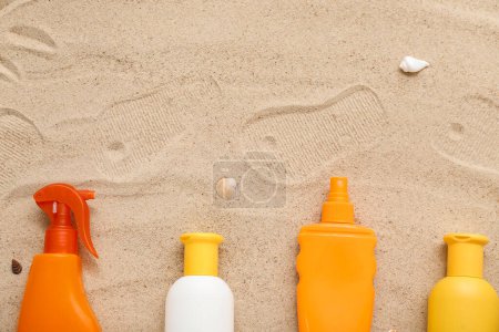 Foto de Composición creativa con diferentes cremas de protector solar y chanclas sobre arena - Imagen libre de derechos